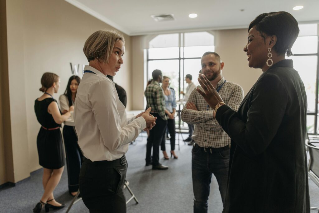 A group of business people standing in a room talking to each other.