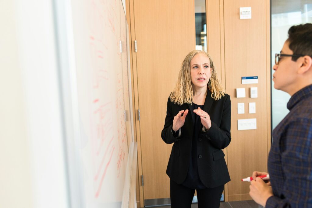 Two colleagues standing at a whiteboard in an office.