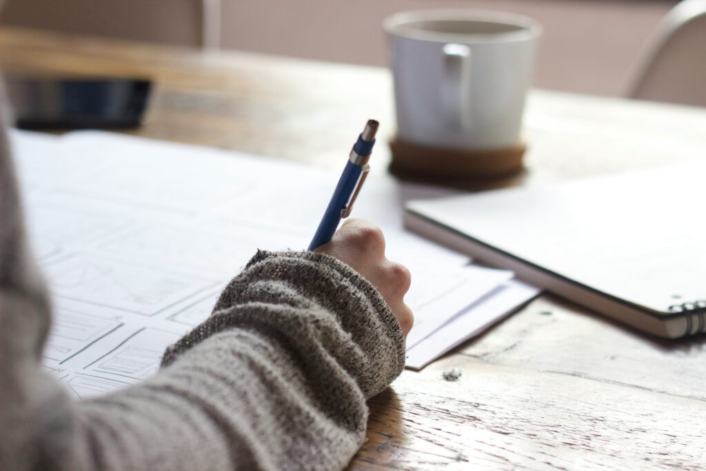 A close up of a person writing notes at a desk.